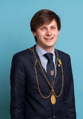 Perth and Kinross Provost Xander McDade with dark brown hair, wearing a navy blue suit and a gold appearing chain of office.