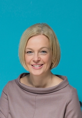 Woman with blonde bobbed hair smiling at the camera