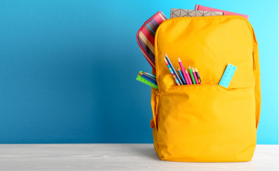 Yellow schoolbag with pencils and pencil cases poking out