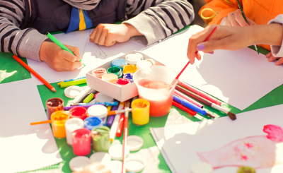 Small children's hands painting brightly coloured pictures