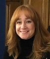Head and shoulders photograph of Zoe Robertson - a woman with long red/auburn hair and a fringe smiling at the camera